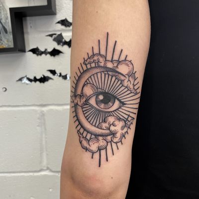 An intricate dotwork and fine line tattoo of clouds, moon, and eye on upper arm. By Jenny Dubet.