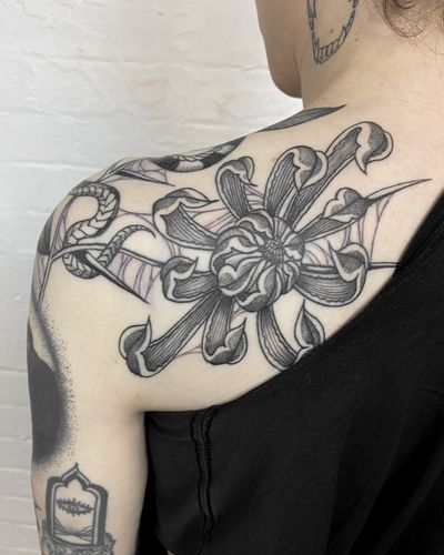 Jenny Dubet's black and gray chrysanthemum tattoo on upper back exudes a sense of calm and elegance.