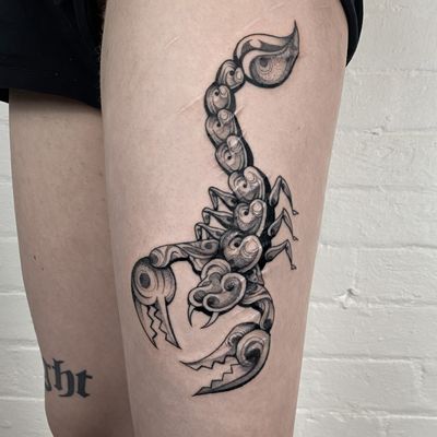 Black and gray tattoo of a scorpion motif on upper leg by Jenny Dubet. Detailed and intricate design.