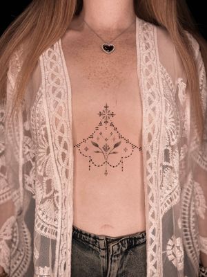 Exquisite dotwork and fine line sternum tattoo featuring ornamental motifs and delicate leaves by Viví Bogdanov.