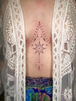 Elegant fine line and ornamental dotwork tattoo featuring delicate leaves by Viví Bogdanov. Perfect for a unique sternum art piece.