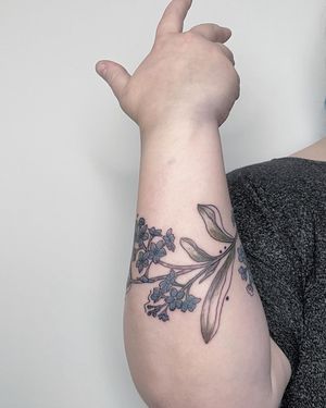 Elegant and delicate blue flower design by Kiky Flore, perfect for a stylish forearm tattoo.