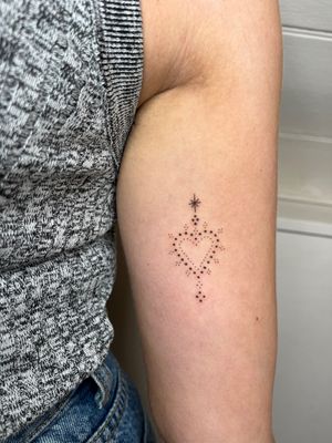 Get a stunning dotwork and fine line heart design on your upper arm by Indigo Forever Tattoos.