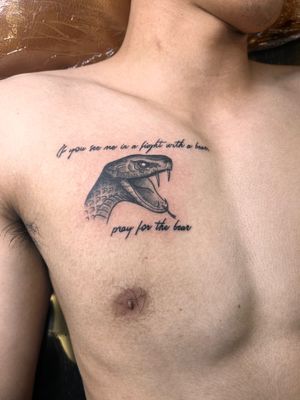Intricate black and gray snake design with small lettering by Kiky Flore, elegantly placed on the chest.