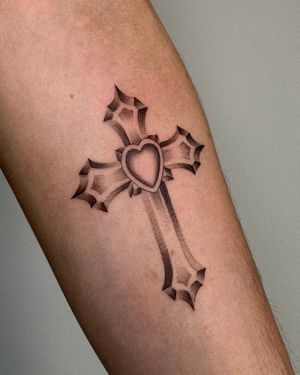 Beautiful black and gray tattoo of a heart intertwined with a cross, by the talented Ophelya Jeandat. A mix of faith and love.