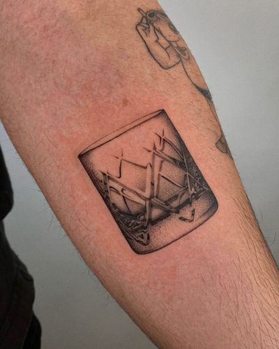 A stunning black and gray tattoo of a crystal and glass motif, expertly inked by Ophelya Jeandat on the arm.
