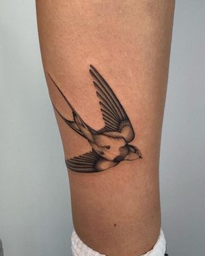 Black and gray swallow tattoo on lower leg by artist Ophelya Jeandat. Elegant and timeless design.