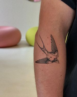 Elegantly detailed swallow tattoo on the arm, expertly crafted in fine line style by the talented artist Ophelya Jeandat.