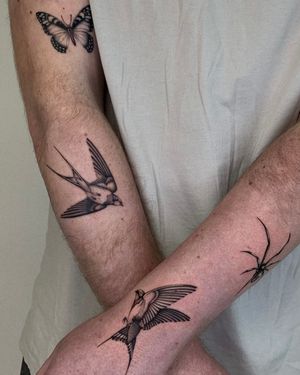 Elegant black and gray swallow tattoo on arm by Ophelya Jeandat. Symbolizes freedom and loyalty.