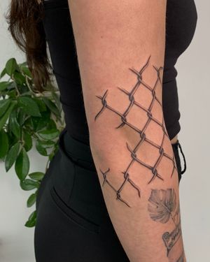 Experience the intricate details of a chain fence brought to life in stunning black and gray by tattoo artist Ophelya Jeandat.