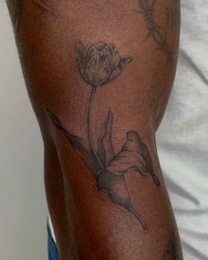 Adorn your arm with a stunning black and gray tulip tattoo by tattoo artist Ophelya Jeandat. Embrace the beauty of nature with this exquisite floral design.