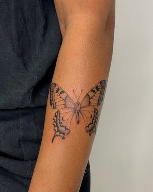 Adorn your arm with a delicate fine line butterfly motif from the talented artist Ophelya Jeandat. A stunning and timeless design.