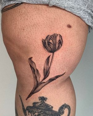 Adorn your upper leg with a beautiful flower tattoo by the talented artist Ophelya Jeandat. Enhance your natural beauty with this elegant design.