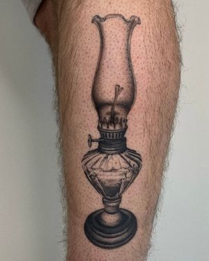 Experience the intricate detail of a black and gray, dotwork, micro-realism tattoo of a vintage oil lamp by the talented artist Ophelya Jeandat.