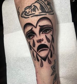 Embrace the duality of emotions with this traditional tattoo by Barney Coles, featuring a heart, sad face, and tears.