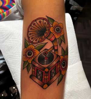 Get a timeless look with this traditional style tattoo featuring a flower, gramophone, and music disc by Barney Coles. Perfect for music lovers!