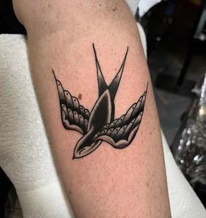 Get a timeless piece of art on your forearm with this classic traditional swallow design by talented artist Barney Coles.