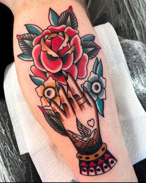 Get inked by Barney Coles with a stunning traditional tattoo featuring a beautiful rose and hands motif on your calf.