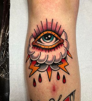 Illustrative traditional tattoo on calf featuring a dramatic eye, cloud, storm, and lightning motif. Expertly executed by artist Barney Coles.