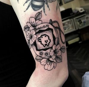 Barney Coles creates a dotwork and fine line illustrative tattoo featuring a nostalgic tamagotchi game in 8-bit style on your arm.