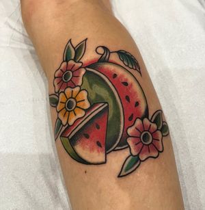 Beautiful traditional tattoo featuring a vibrant flower and juicy watermelon, by artist Barney Coles.