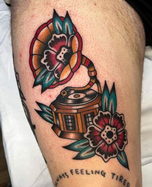 Beautiful traditional tattoo featuring a flower and gramophone design on the thigh by artist Barney Coles.