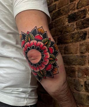 Barney Coles expertly combines bold lines and vibrant colors to create a stunning traditional flower design on the elbow.