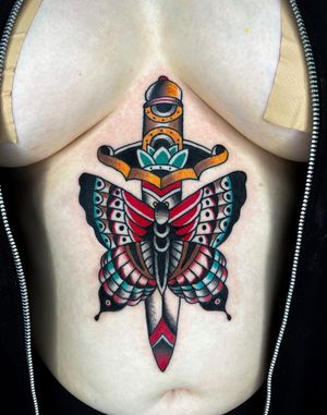 Stunning sternum tattoo by Barney Coles featuring a classic butterfly and dagger motif in traditional style.