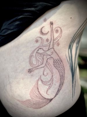 Indigo Forever Tattoos expertly combines dotwork and fine line techniques to create a stunning illustrative design featuring a mystical mermaid under the moonlight.