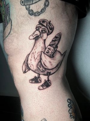 Unique black and gray tattoo featuring a duck and baguette, beautifully executed with dotwork and illustrative style by Claudia Whiteheart.