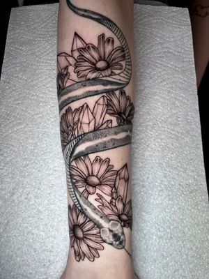 Get a stunning tattoo by Claudia Whiteheart featuring detailed dotwork and fine lines of a beautiful flower and crystal motif.