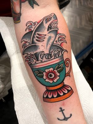 Barney Coles expertly combines a fierce shark with a delicate vase motif in this timeless traditional forearm tattoo design.
