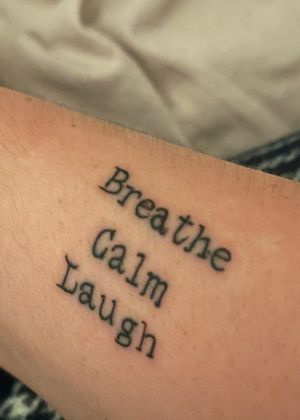 Arm text tattoo saying breathe calm laugh in typewriter print