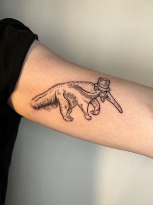 Elegant and whimsical tattoo design by Jonathan Glick, featuring an ant eater wearing a monocle and top hat in fine line illustrative style.