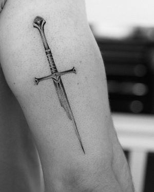 Experience the power of the Lord of the Rings with this stunning black and gray micro-realism tattoo of the iconic Narsil sword. Let Victoria bring your fantasy to life!