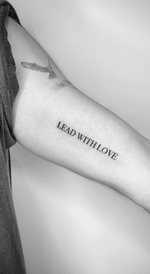 Small lettering tattoo by Math with a powerful message to guide your actions with love and compassion.