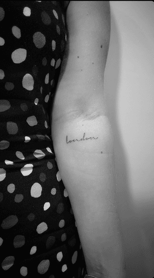 Capture the essence of London with this fine line cursive tattoo by Math. Perfect for those who love the city life.