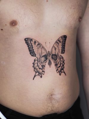 Fine line illustrative tattoo by Oscar Jesus featuring a butterfly, moth, and skull design in black and gray.