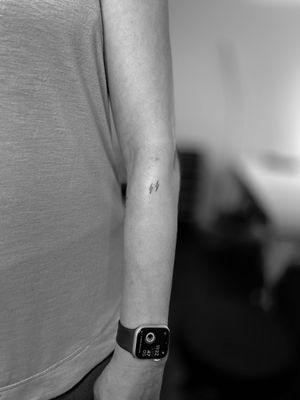 Get electrified with this fine line tattoo by Vera featuring a minimal lightning bolt design.