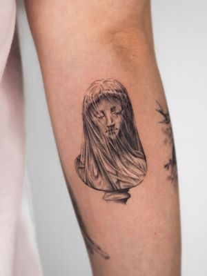 Experience the intricate detail of micro realism with this black and gray tattoo of the iconic veiled virgin statue, by Oscar Jesus.