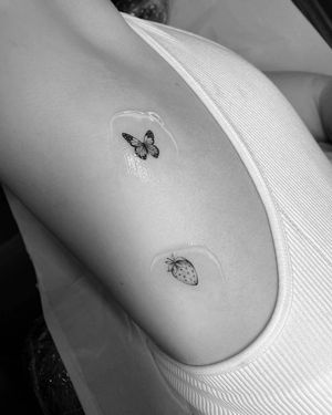 Experience the delicate beauty of fine line micro-realism with Vera's illustrative butterfly and strawberry tattoo design.