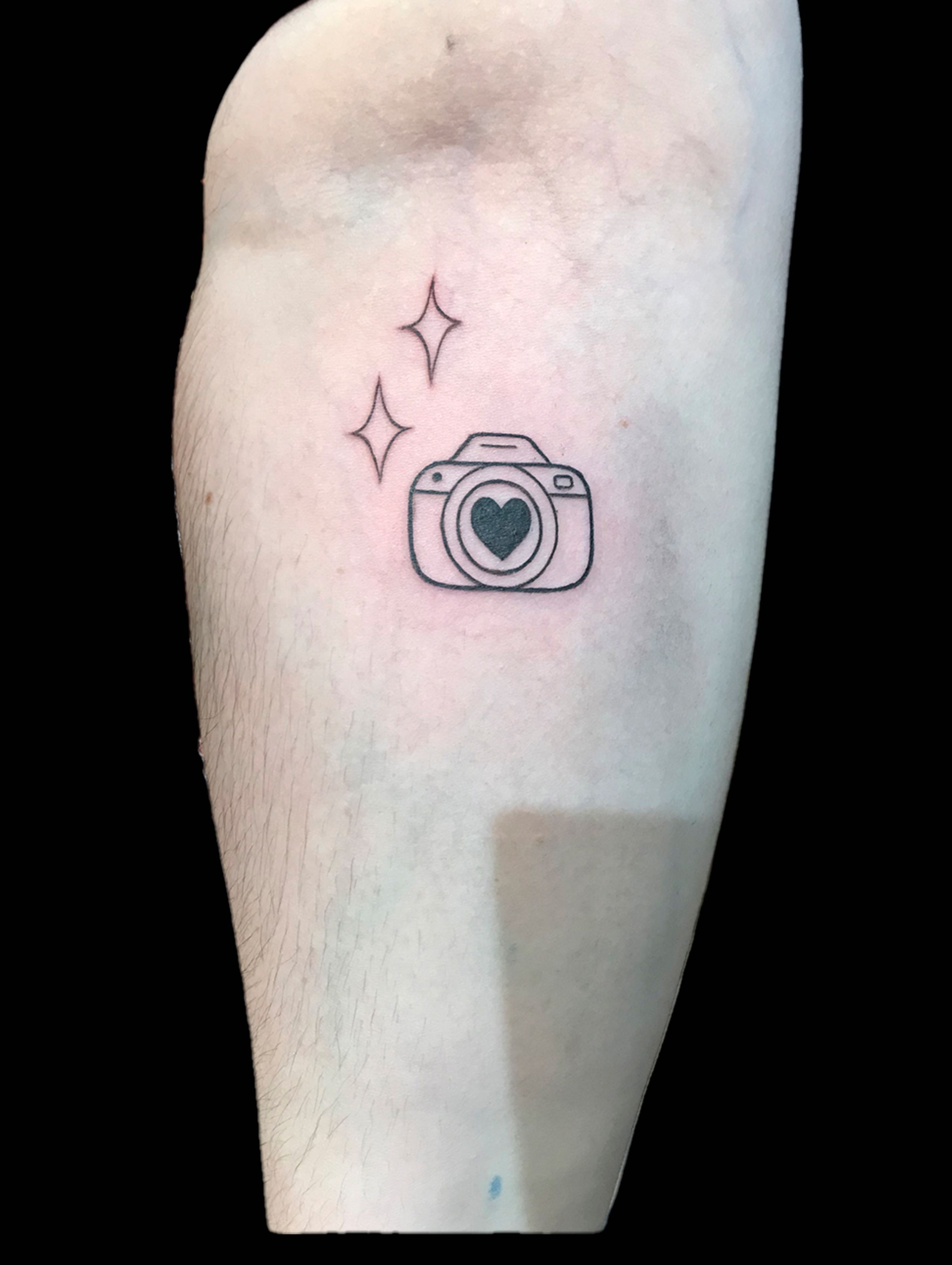 Tiny fine line reflex camera tattooed on the wrist.