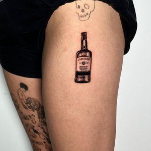 Delicate black and gray micro-realism tattoo of a whisky bottle, crafted by the talented artist Seven.