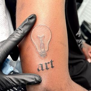 Get inspired by Seven's fine line and illustrative style tattoo featuring a lamp or light bulb motif, perfect for art lovers.