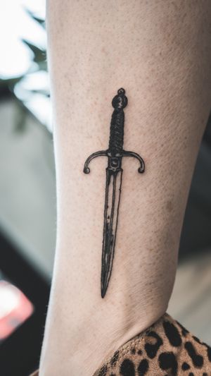Elevate your style with a sharp and detailed sword tattoo by Seven, blending traditional and modern illustrative techniques.