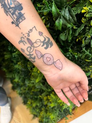 Embrace your sweet side with this glittery candy-inspired tattoo by Rachel Angharad. The fine line work and illustrative style will make this tattoo a standout piece.