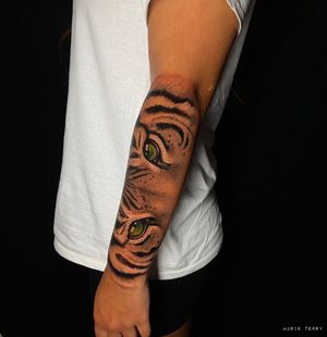 Impressive arm tattoo of mesmerizing tiger eyes by Marie Terry, showcasing remarkable realism.
