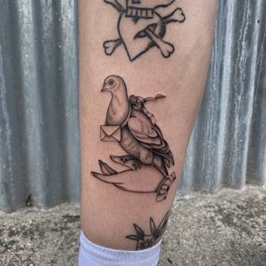 Beautiful black and gray tattoo of a pigeon carrying a letter, by the talented artist Charlie Macarthur.