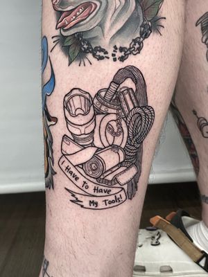 Small lettering and illustrative tattoo by Liam Collins featuring BDSM, camping, and flashlight motifs.