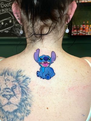 Vibrant new school upper back tattoo featuring the beloved characters Lilo and Stitch, created by artist Liam Collins.